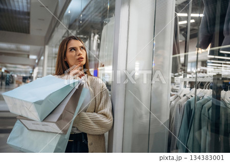 Thinking what to buy. Beautiful woman is in the mall, conception of shopping Thinking what to buy. Beautiful woman is in the mall, conception of shopping 134383001
