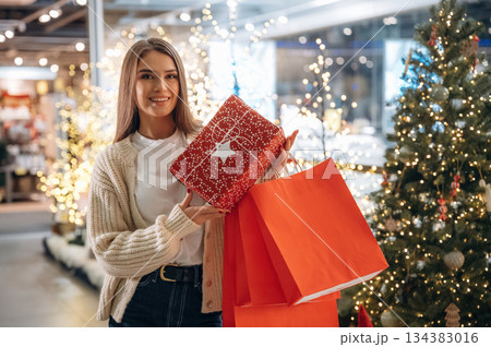 Holding bags. New year shopping and presents. Woman is near the Christmas tree 134383016