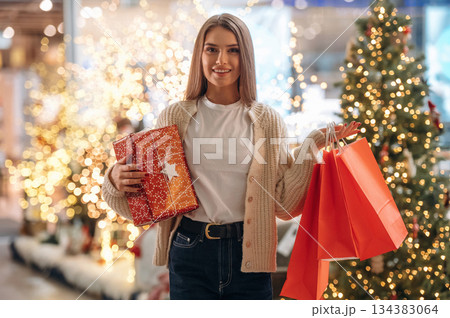 Gift in hands. New year shopping and presents. Woman is near the Christmas tree 134383064
