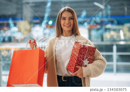 Cheerful facial expression, standing. New year shopping and presents. Woman is near the Christmas tree 134383075
