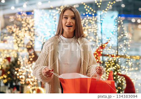 Surprised by the gift. New year shopping and presents. Woman is near the Christmas tree Surprised by the gift. New year shopping and presents. Woman is near the Christmas tree 134383094
