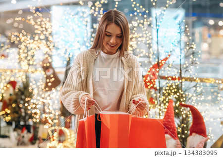 Surprised by the gift. New year shopping and presents. Woman is near the Christmas tree Surprised by the gift. New year shopping and presents. Woman is near the Christmas tree 134383095