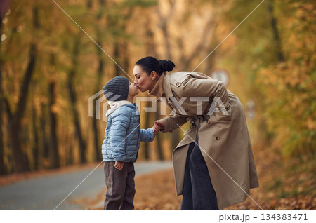 Mother with her son are having a walk in autumn forest near the road Mother with her son are having a walk in autumn forest near the road 134383471