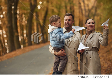 With paper planes. Happy family are together in the autumn forest near the road 134383521