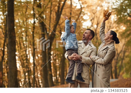 Happy family are together in the autumn forest near the road Happy family are together in the autumn forest near the road 134383525