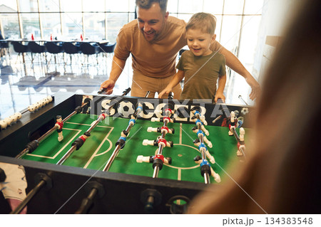 Conception of entertainment. Father and son are playing table football game indoors Conception of entertainment. Father and son are playing table football game indoors 134383548