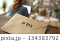 FBI Envelope on Wooden Desk, Person Working in Background 134383792