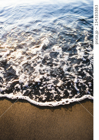 夕暮れの砂浜に打ち寄せる波と輝く水面 134383863