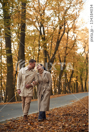 Smiling, hawing a walk. Lovely couple are together in the autumn forest near the road Smiling, hawing a walk. Lovely couple are together in the autumn forest near the road 134384034