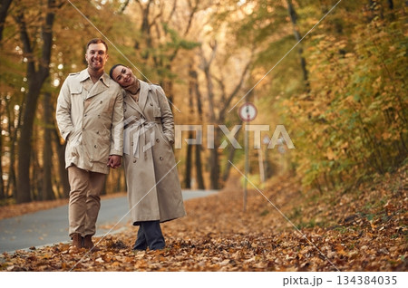 Smiling, hawing a walk. Lovely couple are together in the autumn forest near the road Smiling, hawing a walk. Lovely couple are together in the autumn forest near the road 134384035