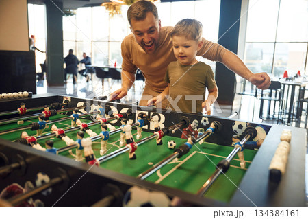 Conception of entertainment. Father and son are playing table football game indoors 134384161