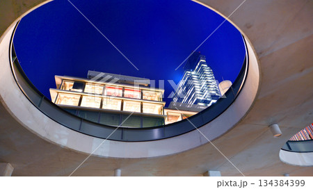 Office building in the evening with lightened workspaces. Modern, glazed skyscraper in financial district. Late hours in the office. 134384399