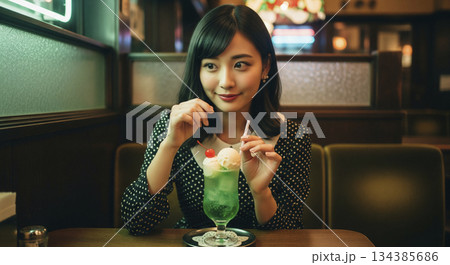 レトロ喫茶でクリームソーダを食べる女性 134385686