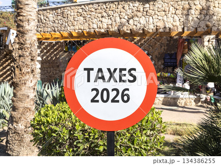 Taxes 2026 new year symbol. Concept words Taxes 2026 on beautiful white and red road sign. Beautiful palm trees palm-trees background. Business and taxes 2026 new year concept. Copy space Taxes 2026 new year symbol. Concept words Taxes 2026 on beautiful white and red road sign. Beautiful palm trees palm-trees background. Business and taxes 2026 new year concept. Copy space 134386255