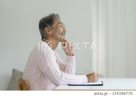 ペンを持って書き物をするシニア男性 134386770