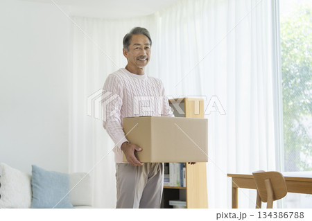 ダンボール箱を持ったシニア男性　カメラ目線　引越し・断捨離　イメージ　 134386788