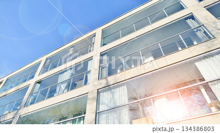 Futuristic square architecture of apartment building. Real estate with panoramic windows and blue sky with clouds. Futuristic square architecture of apartment building. Real estate with panoramic windows and blue sky with clouds. 134386803