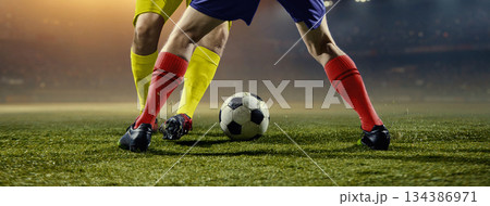 Dynamic football leg battle with rapid direction change under stadium lights. Dynamic football leg battle with rapid direction change under stadium lights. 134386971