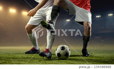 Fast paced football action with two players legs battling for ball on stadium pitch. Fast paced football action with two players legs battling for ball on stadium pitch. 134386980