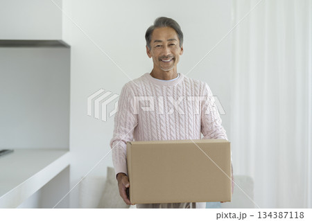カメラ目線で笑顔のダンボール箱を持った60代の男性 引越し・断捨離 イメージ カメラ目線で笑顔のダンボール箱を持った60代の男性 引越し・断捨離 イメージ 134387118