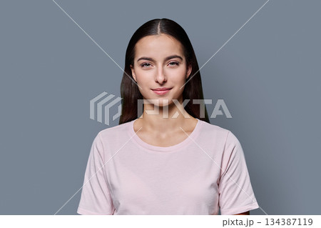 Portrait of beautiful smiling teenage girl against gray studio background Portrait of beautiful smiling teenage girl against gray studio background 134387119