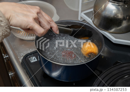 渋柿を熱湯にくぐらせて消毒し干し柿を作っている 134387253