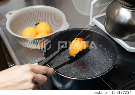 渋柿を熱湯にくぐらせて消毒し干し柿を作っている 134387254