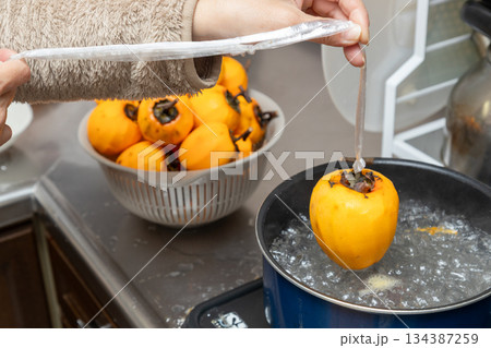 渋柿を熱湯にくぐらせて消毒し干し柿を作っている 134387259