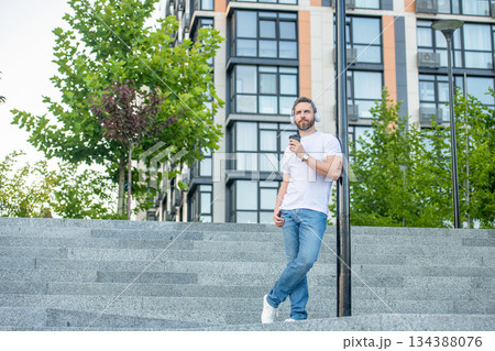 photo of man in music headphones with coffee cup. man in music headphones outdoor. photo of man in music headphones with coffee cup. man in music headphones outdoor. 134388076