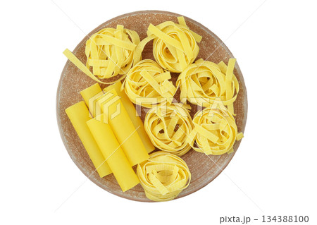 Various of uncooked pasta. Fettuccine, tagliatelle and cannelloni on ceramic plate isolated on white background. Top view. 134388100