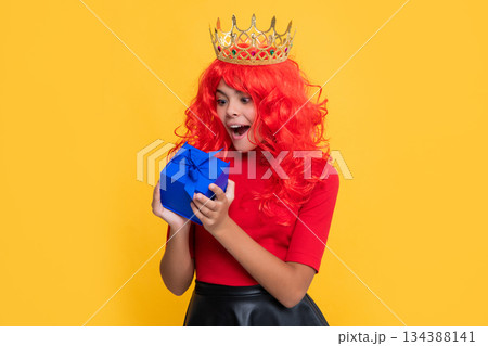 surprised child in crown with gift box on yellow background 134388141