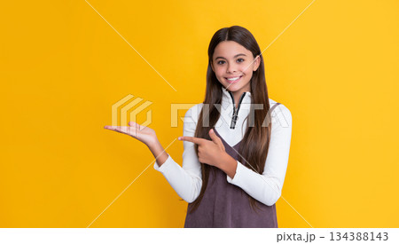 happy child with long hair on yellow background. presenting product 134388143