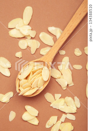 Fresh almond flakes in spoon on brown background. Fresh almond flakes in spoon on brown background. 134388510