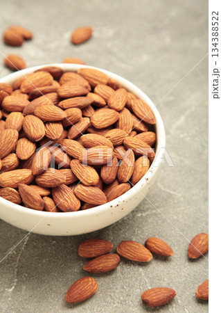 Almonds in bowl on grey background. Whole and dried nuts. Vertical photo Almonds in bowl on grey background. Whole and dried nuts. Vertical photo 134388522
