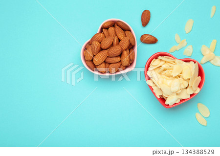 Fresh almond flakes and nuts in bowl on blue background 134388529