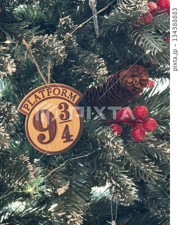 Christmas ornament on tree with platform nine and three-quarters design and shiny red berries Christmas ornament on tree with platform nine and three-quarters design and shiny red berries 134388883