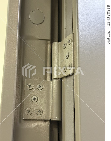 Metal hinge of a gray door with detailed screws and texture, suitable as industrial background Metal hinge of a gray door with detailed screws and texture, suitable as industrial background 134388889