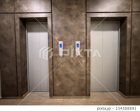 Elevator doors with metallic finish in modern building interior, ideal as architecture background Elevator doors with metallic finish in modern building interior, ideal as architecture background 134388891