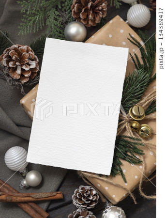 Card on wrapper Christmas present near pine cones, spices and fir twigs, top view. Holiday mockup Card on wrapper Christmas present near pine cones, spices and fir twigs, top view. Holiday mockup 134389417