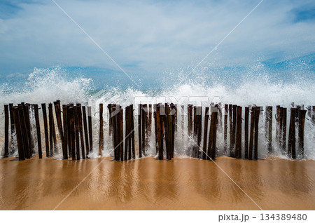 Powerful wave hit the wooden walls making white splashing water droplets in the air. Powerful wave hit the wooden walls making white splashing water droplets in the air. 134389480