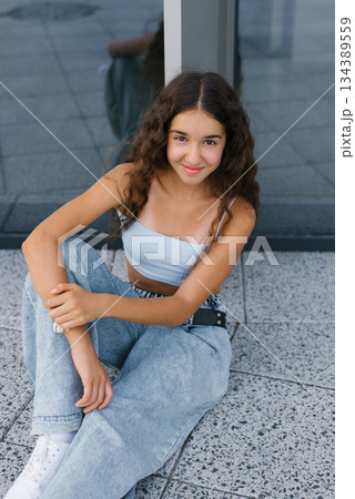 Happy Teen Sitting By Glass Wall 134389559