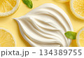 Creamy white dessert topping swirled with lemon slices and fresh mint garnishing on a bright yellow background 134389755