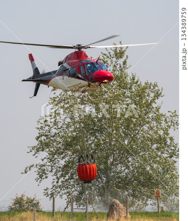 Helicopter in Action with Firefighting Water Bucket 134389759