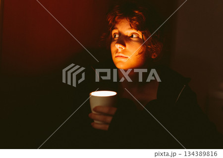 young woman with a candle in a dark room young woman with a candle in a dark room 134389816