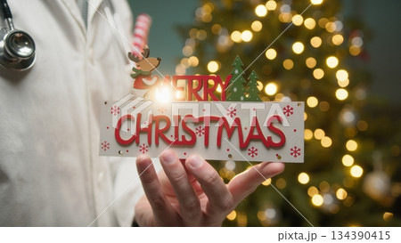 Cardiologist Doctor Wishes Merry Christmas in Front of Glowing Tree 134390415