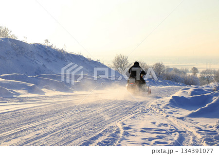 Outdoor winter sports in Russia.In the photo, athletes on snowmobiles ride on snowy off-road, in a wild impassable area.Surrounded by a beautiful winter backdrop with trees covered in frost Outdoor winter sports in Russia.In the photo, athletes on snowmobiles ride on snowy off-road, in a wild impassable area.Surrounded by a beautiful winter backdrop with trees covered in frost 134391077