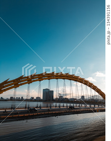 Golden Dragon Bridge over Han River in Da Nang at sunset, Iconic Vietnamese landmark spanning urban waterway with city skyline view 134391156