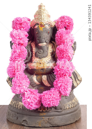 Ganesha idol adorned with pink flower garland for Ganesha Chaturthi festivals. 134391241