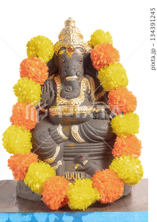 Ganesha idol decorated with marigold garland for Hindu festival, prayers and blessings 134391245