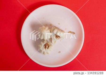 Steamed sweet modak rice dumplings on a white plate against a bright red background Steamed sweet modak rice dumplings on a white plate against a bright red background 134391289